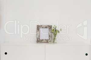 Picture frame, perfume bottle and flora on table