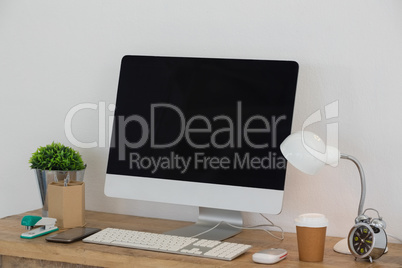 Electric lamp, mobile phone, desktop pc, disposable glass, flora and stationery on table