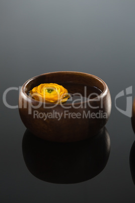 Yellow rose in glass bowl with water on black background