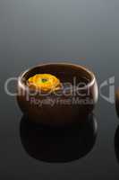 Yellow rose in glass bowl with water on black background