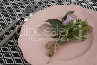 Fork and butter knife with flower and plate arranged on table cloth