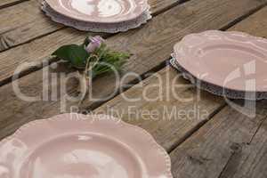 Plates with rose flower arranged on wooden table