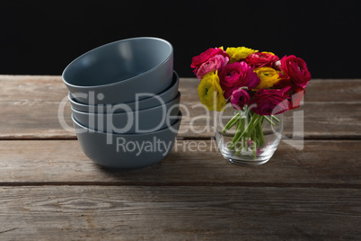 Stack of bowls and flowers on wooden plank