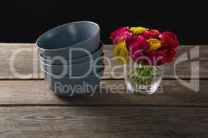 Stack of bowls and flowers on wooden plank