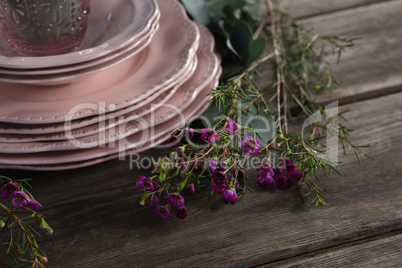 Crockery and floral decorations on wooden plank