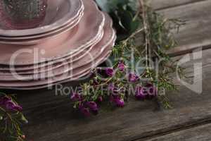 Crockery and floral decorations on wooden plank