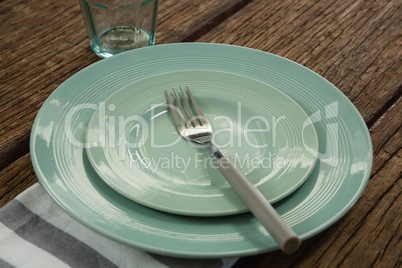 Plate with fork and napkin on wooden table