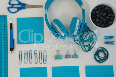 Headphones, blueberries and stationery on white background