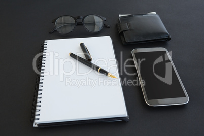 Spectacles, organizer, pen, mobile phone and wallet on background