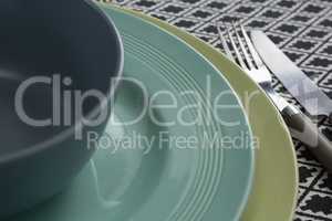 Fork and butter knife with bowl and plates on table cloth