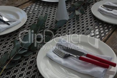 Plate with fork, butter knife and napkin on wooden table