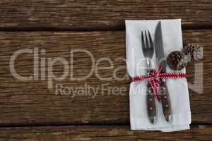 Pine cone with fork, butter knife and napkin tied up with ribbon
