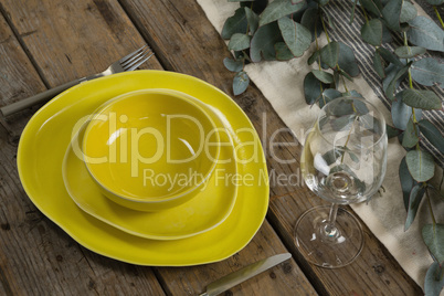 Stack of various dinnerware with cutlery and empty glass