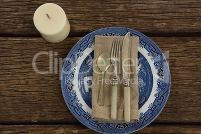 Cutlery and napkin on plate with candle