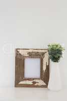 Wooden frame and vase against white wall