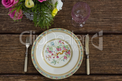 Fork and butter knife with plate arranged on wooden table