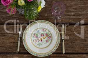 Fork and butter knife with plate arranged on wooden table