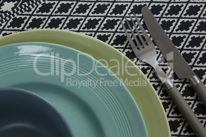 Fork and butter knife with bowl and plates on table cloth