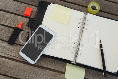 Mobile phone and office supplies on wooden plank