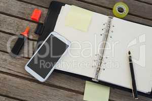 Mobile phone and office supplies on wooden plank