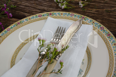 Fork and butter knife with flower and napkin on wooden table