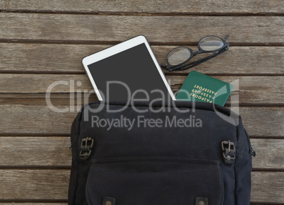 Bag with passport spectacles and digital tablet on wooden plank