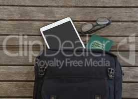 Bag with passport spectacles and digital tablet on wooden plank