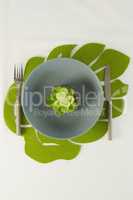 Flower in bowl with fork and butter knife on a table cloth