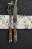 Fork and butter knife with flower and table cloth on black background