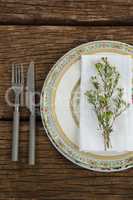 Flora and napkin arranged on plate with cutlery