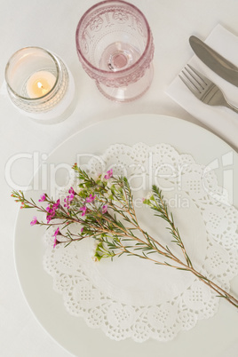 Flower kept over an embroidery napkin plate with cutlery