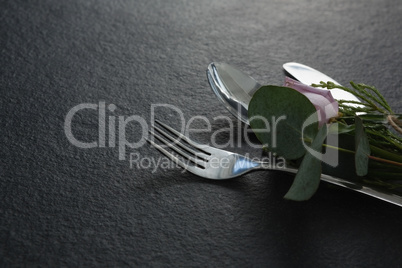 Fork and butter knife with flower on black background