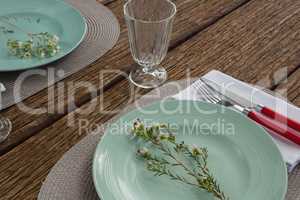 Fork and butter knife with napkin and flower on plate