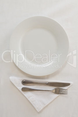 Empty plate with fork, butter knife and napkin