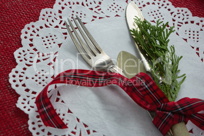 Cutlery with fern tied up with ribbon on a placemat