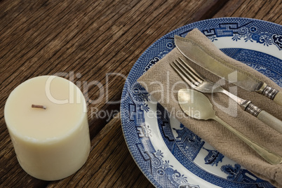 Cutlery and napkin on plate with candle