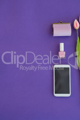 Tulips, purse, nail polish and mobile phone arranged on purple background