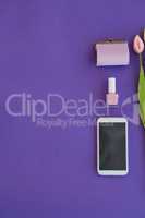 Tulips, purse, nail polish and mobile phone arranged on purple background