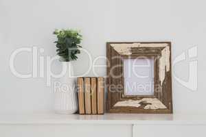 Wooden frame, vase and books arranged on table