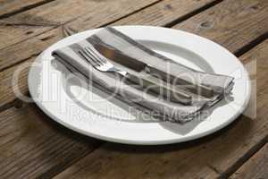 Fork and butter knife with napkin arranged in a plate