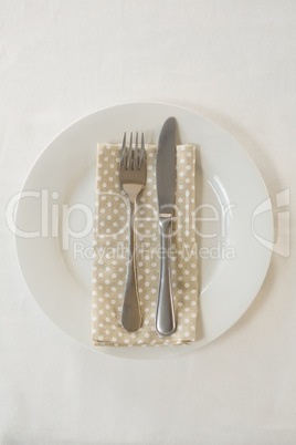 Fork and butter knife with napkin arranged in a plate