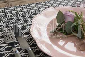 Fork and butter knife with flower and plate arranged on table cloth