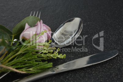 Fork and butter knife with flower on black background