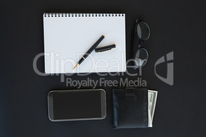 Spectacles, organizer, pen, mobile phone and wallet on background