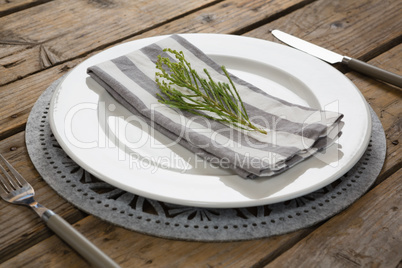 Fork and butter knife with napkin and herb in a plate