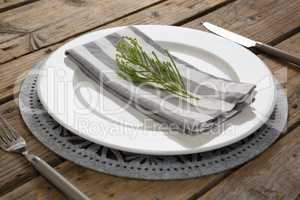 Fork and butter knife with napkin and herb in a plate