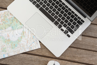 Laptop and world map on wooden plank