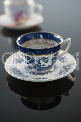 Empty cup with saucer and spoon on black background