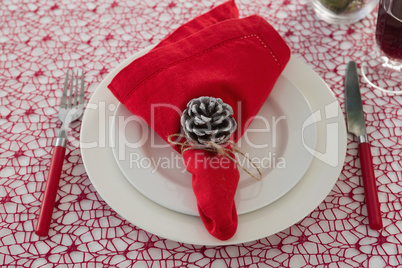 Pine cone and napkin on a plate with fork and butter knife