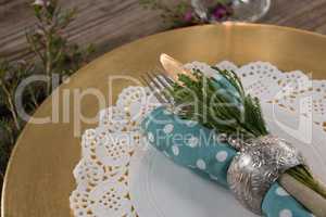 Folded napkin with cutlery and flora placed on palcemat